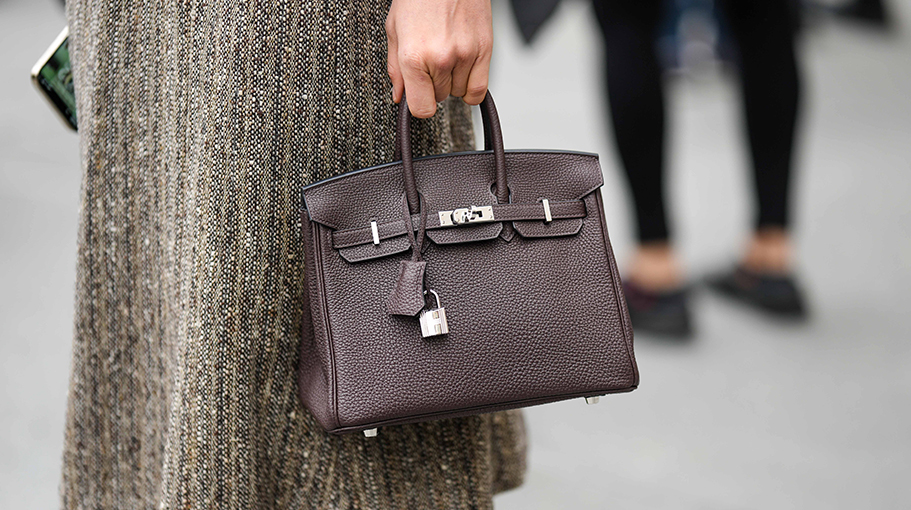 NEW YORK, NEW YORK - FEBRUARY 12: A guest wears a gray wool knees skirt from Dior, a dark brown shiny leather Birkin handbag from Hermes, outside Jason Wu, during New York Fashion Week, on February 12, 2023 in New York City.