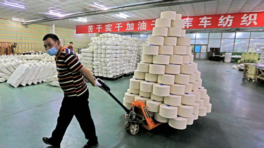 A worker handles spools of yarn on a production line at a workshop of Xinjiang Xieyi Textile Technology Co., Ltd on March 30, 2021 in Kuqa, Xinjiang Uygur Autonomous Region of China.