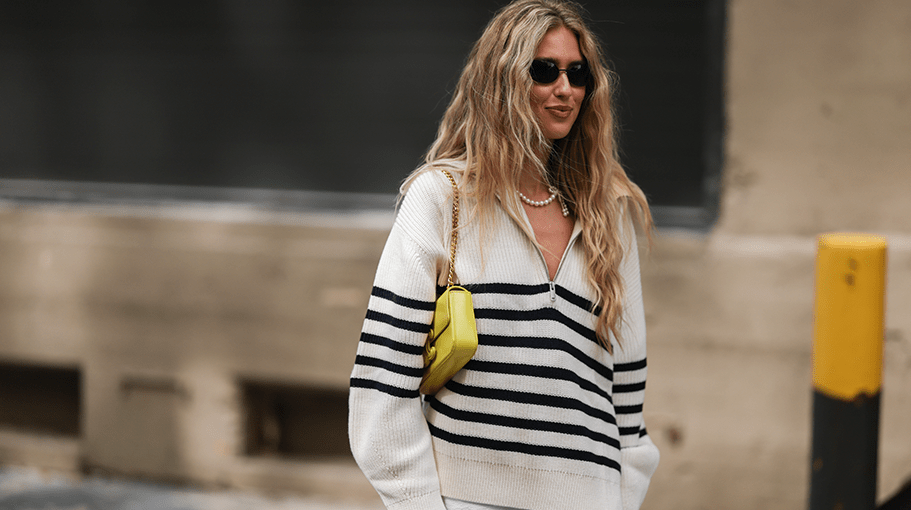 Emili Sindlev is seen wearing black sunglasses, pearl necklace, white striped wool knit sweater with a zipper, white short skirt and a yellow leather Celine shoulder bag, outside COS, during New York Fashion Week on September 13, 2022 in New York City.