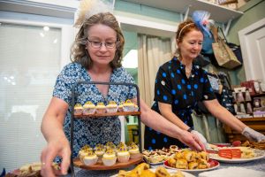 Workers wearing fascinators put out cupcakes and small pastries during a tea service as they celebrate the coronation of King Charles III at The Bee's Knees British store in Acton, Massachusetts, on May 6, 2023. (Photo by Joseph Prezioso / AFP) (Photo by JOSEPH PREZIOSO/AFP via Getty Images)