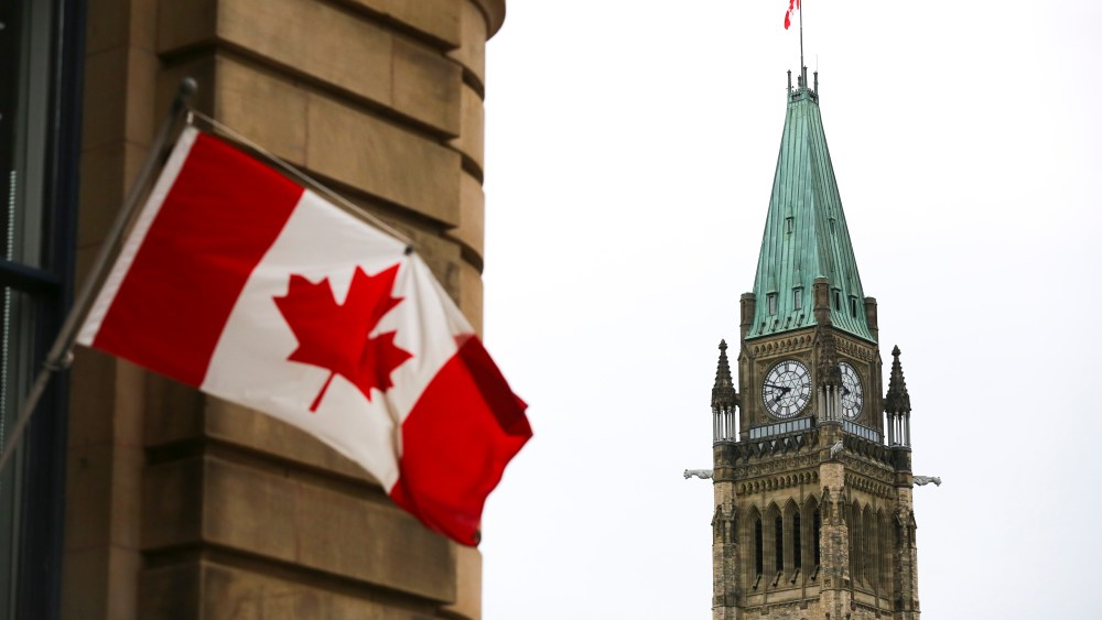 The Canadian Flag flies on a building in Ottawa across from the Peace Tower on Centre Block of Parliament Hill.