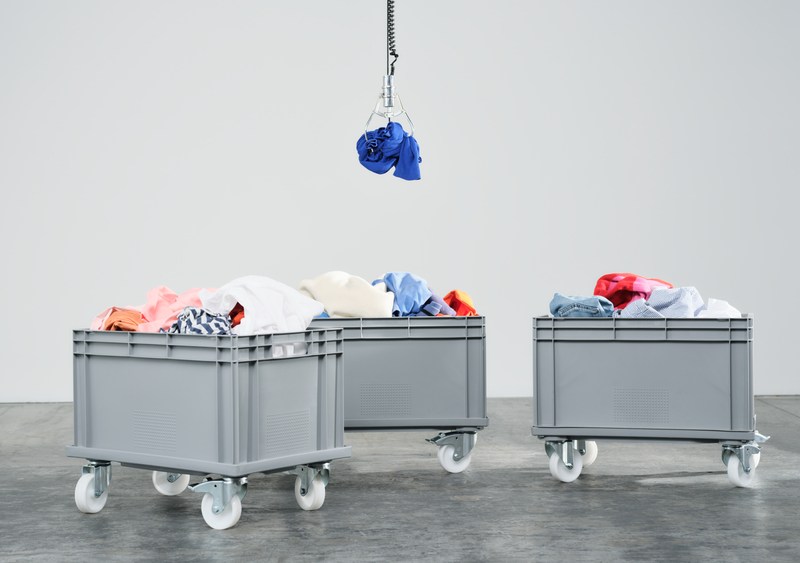 Global Change Award 2023 winner Refiberd shown here with a claw-like vending machine arm poised over three colorful trollies of clothing waste.