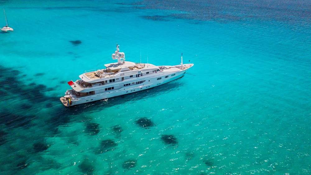 Big luxury yacht anchoring in shallow water, aerial view. Active life style, water transportation and marine sport.