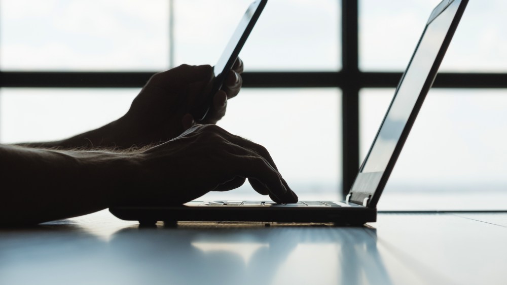 secure online payments. two factor authorization. man hands holding mobile phone and entering password message on laptop.