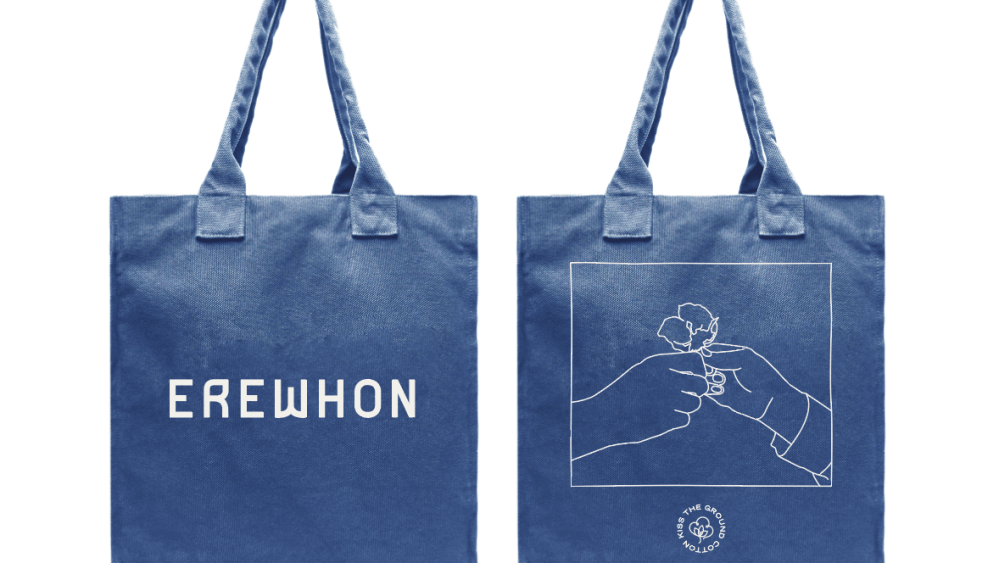 A denim tote at Erewhon sells for $135 but tells a deeper story on regenerative cotton. The design has "Erewhon" in bold white lettering with a drawing on back of hands passing over a flower.