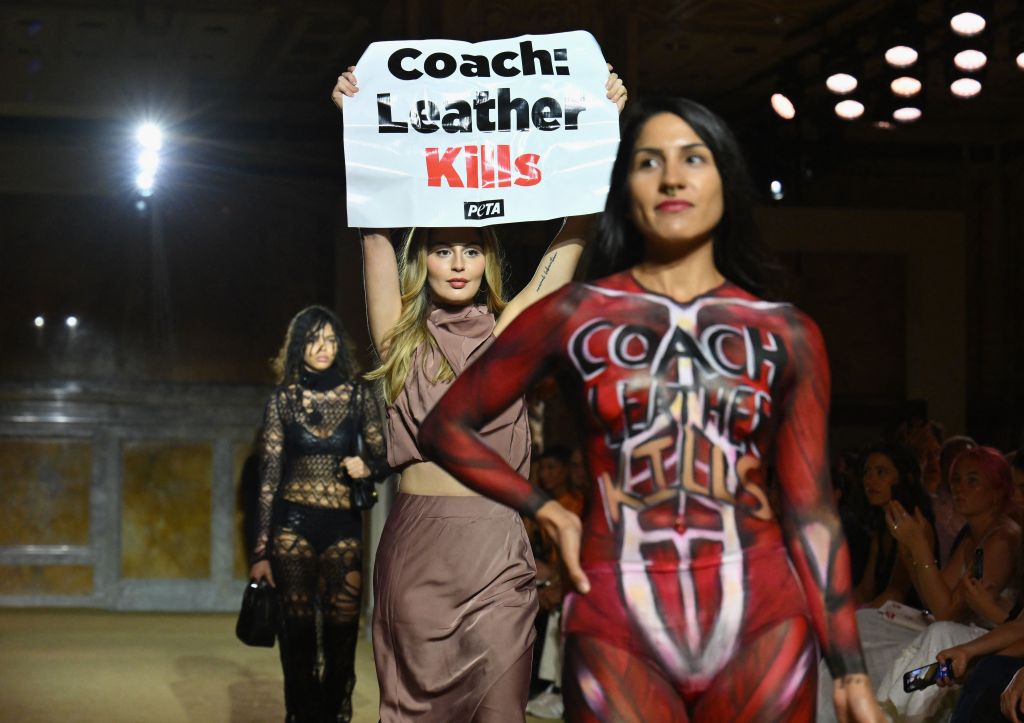 TOPSHOT - A Peta protester holds a sign reading "Coach: Leather Kills" as she demonstrates on the runway during the Coach Spring 2024 show during New York Fashion Week in New York City on September 7, 2023. (Photo by ANGELA WEISS / AFP) (Photo by ANGELA WEISS/AFP via Getty Images)