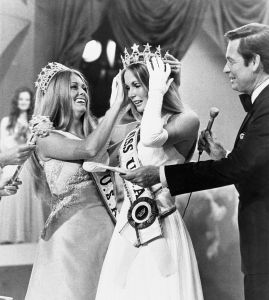 Tanya Wilson, 21, of Honolulu, is crowned Miss U.S.A. of 1972 by Michele McDonald, of Butler, Pennsylvania, Miss U.S.A. of 1971, at conclusion of annual pageant. At right is Bob Barker, master of ceremonies.