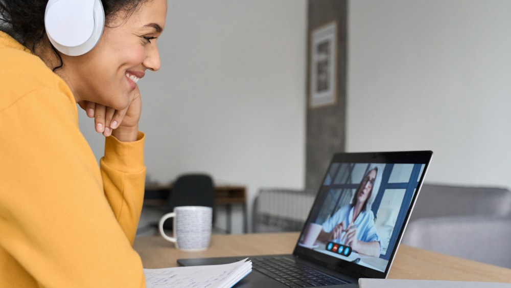 African American mixed race adult student wearing headphones having virtual meeting online call with teacher, educational webinar chatting at home office. Video e learning conference call on pc.