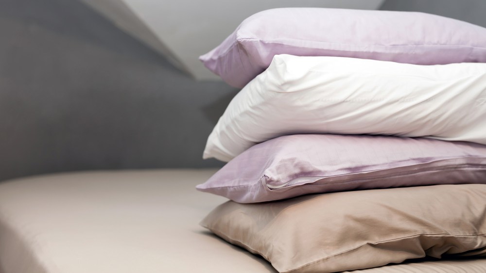 four pillows dressed in different-colored pillowcases stacked one on top of the other