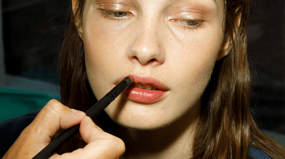 woman applying lipstick with a small brush