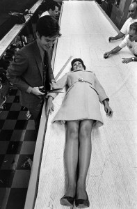 Designer Calvin Klein cuts a pattern around a model wearing a pink wool knit coat from the Halldon collection, worn over a pink and white striped dress.