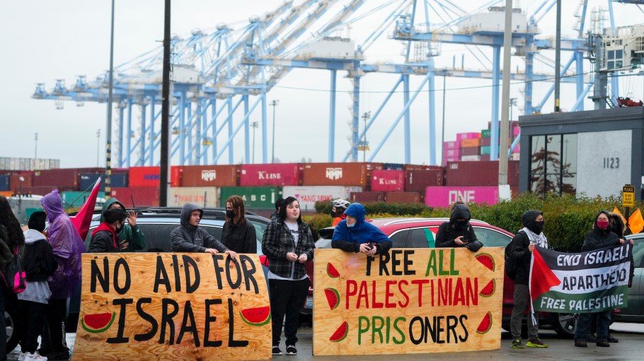 Protesters hold up large wooden signs as they block the main Port of Tacoma entrance to delay the loading of the Cape Orlando vessel, Monday, Nov. 6, 2023, in Tacoma, Wash.