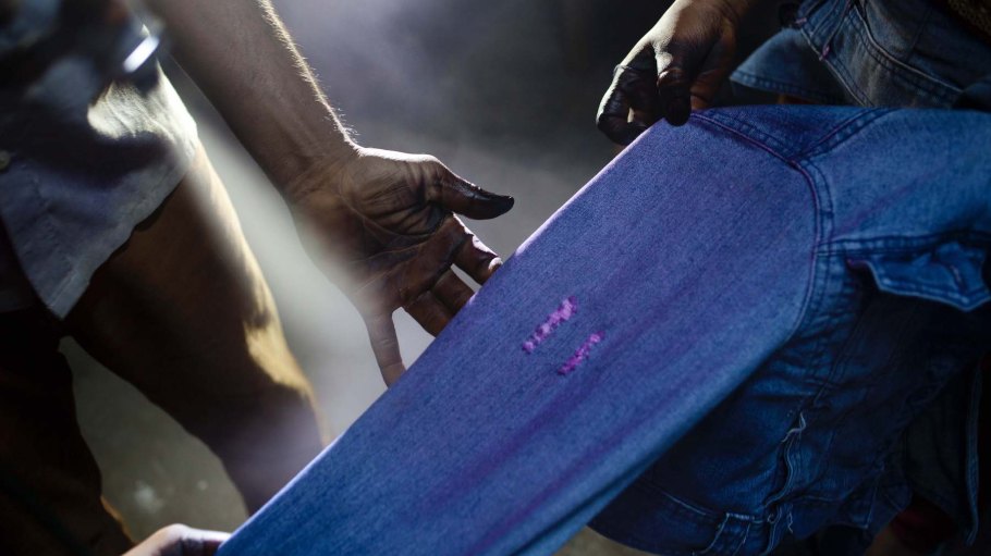 Workers are spraying potassium permanganate on the denim for fading the color in a washing factory on May 22, 2013 in Dhaka, Bangladesh.