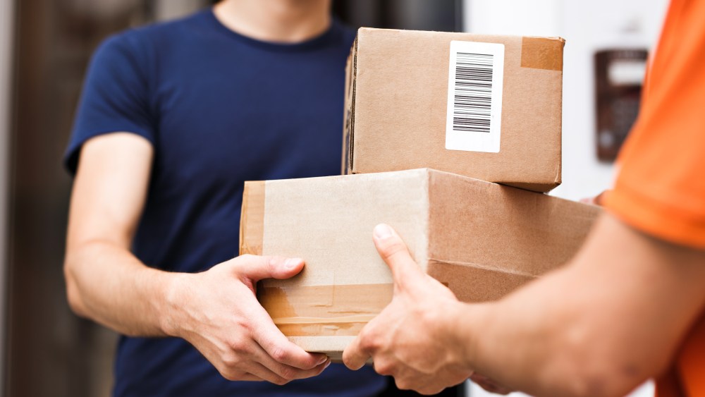 A person wearing an orange T-shirt is delivering parcels to a satisfied client. Friendly worker, high quality delivery service.