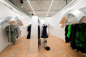 Arches of galvanized steel shelter racks of avant-garde women’s clothing.