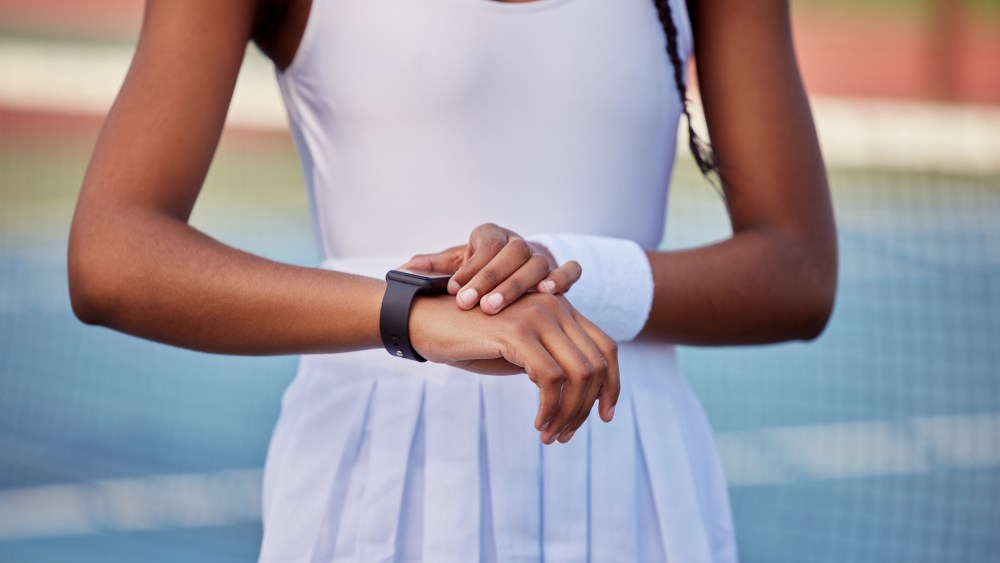 Woman, tennis and smart watch for outdoor training with check heart rate, health info and body stats. Sports athlete, wearable tech and monitor performance for workout, progress and app data on court.