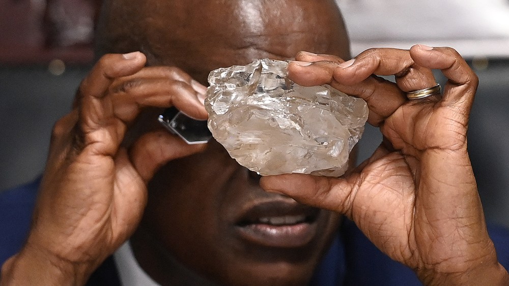 Botswana's President Mokgweetsi Masisi looks at a large diamond discovered in Botswana at his office in Gaborone on August 22, 2024. The 2492 carat diamond was discovered in the Karowe mine in Botswana of Lucara Diamond Company. Botswana is one of the world's largest producers of diamonds, which constitute its main source of income, representing 30% of GDP and 80% of its exports. (Photo by Monirul BHUIYAN / AFP) (Photo by MONIRUL BHUIYAN/AFP via Getty Images), world's largest diamond, second largest diamond, 2,492-carat