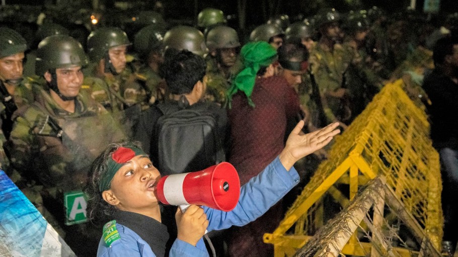 Army personnel stand guard behind barricades as a student shouts slogans during a protest outside the residence of Bangladesh's president Mohammed Shahabuddin, demanding his resignation amid accusations of his residual loyalty to the toppled premier Sheikh Hasina, in Dhaka on October 22, 2024.