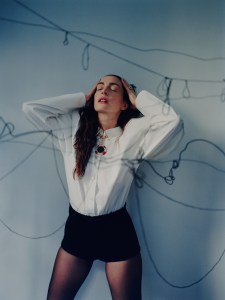 Nina Ricci by Harris Reed cotton poplin puff-sleeve shirt; Dior velvet shorts; Commando tights; Bulgari High Jewelry Monete necklace in pink gold with coral elements, bronze coin and pavé-set diamonds; Bulgari B.zero1 18-karat yellow gold three-band ring set with demi-pavé diamonds on the edges; Bulgari Serpenti Viper onecoil 18-karat yellow gold ring; Serpenti Viper two-coil 18-karat white gold ring set with pavé diamonds.