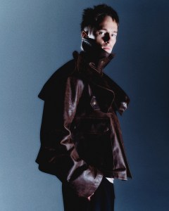 JW Anderson leather sculptural trench coat over Dries Van Noten jersey tank; Saint Laurent by Anthony Vaccarello silk crepe wide leg trousers.