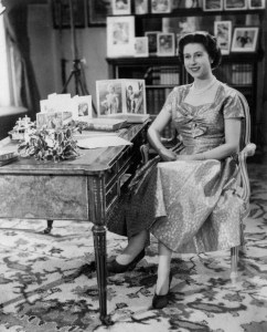 The Queen, in a gold lame dress, is seen in the Long Library at Sandringham shortly after making the traditional Christmas Day broadcast to her peoples. On the desk are portraits of Prince Charles and Princess Anne. The broadcast was televised this yer for the first time and was carried by both the BBC and ITV. It was the 25th anniversary of the first radio message to the Commonwealth by her grandfather, King George V.