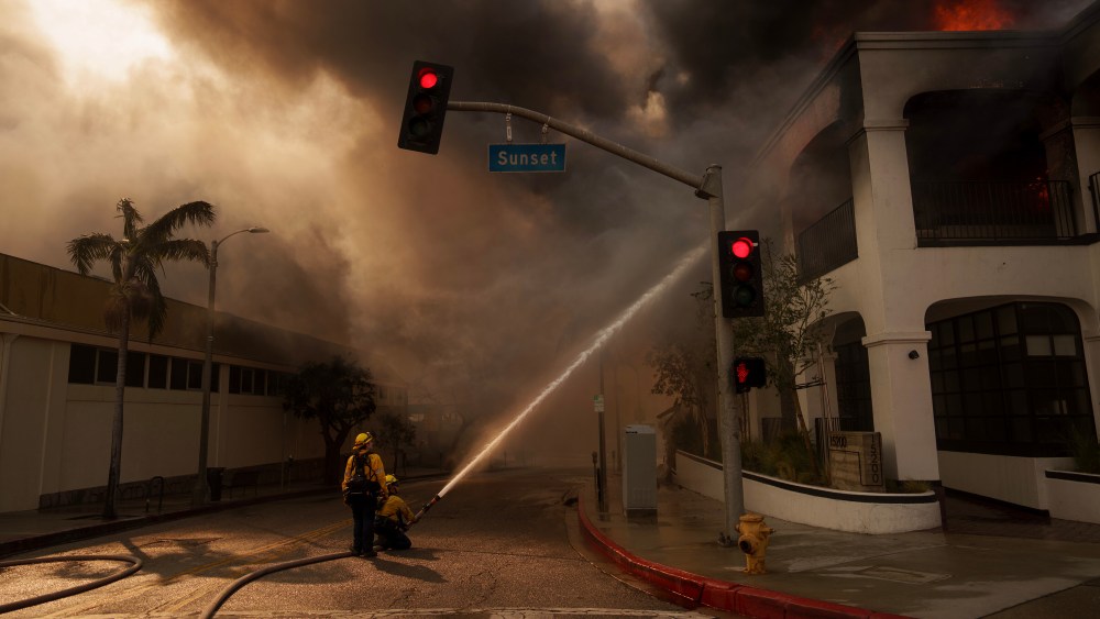 Firefighters spray flames from the Palisades Fire burning a business on Jan. 8, 2025 in the Pacific Palisades neighborhood of Los Angeles. Multiple wildfires fueled by intense Santa Ana winds are burning across Los Angeles County. Five people have been killed, over 25,000 acres have burned, and 30,000 people have been evacuated.