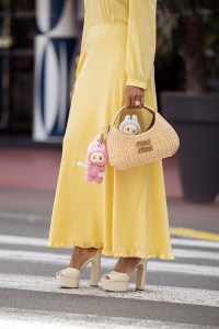 CANNES, FRANCE - MAY 17: Zufi Alexander wears an all Miu Miu look made of butter yellow long summer dress, off white pumps high heels with platform, and straw Miu Miu bag with attached Labubu bag charms during day five of the 78th Cannes Film Festival on May 17, 2025 in Cannes, France. (Photo by Raimonda Kulikauskiene/Getty Images)