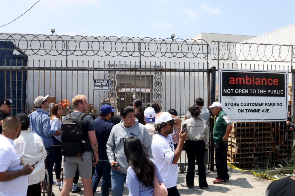 LOS ANGELES, CA  - JUNE 6, 2025 - -  People gather in front of Ambiance Apparel after several employees were taken into custody by federal agents in the Garment District in downtown Los Angeles on June 5, 2025. Protesters gathered at that location and at one point, federal agents had to shove  protesters out of the path of a van that was being driven into the building's parking lot. (Genaro Molina/Los Angeles Times via Getty Images)
