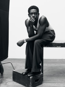 Hanro cotton tank top; Lanvin wool-woven pleated trousers; Amiri belt; Ferragamo shoes; IWC Ingenieur Automatic 35 gold-colored watch with gold case; all jewelry by Didris.