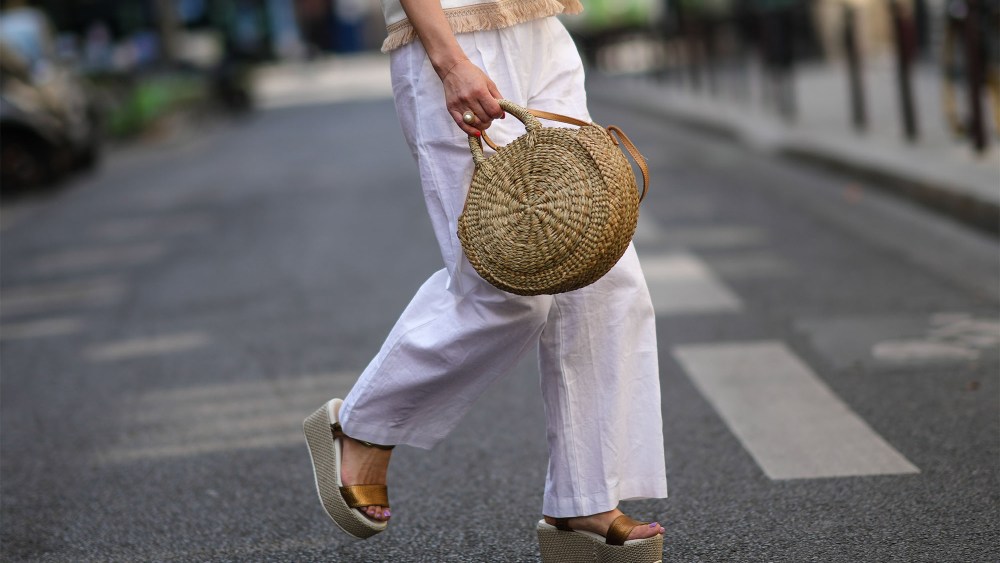 woman wearing linen pants and carrying a straw bag