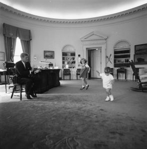ST-441-10-62 10 October 1962 President John F. Kennedy claps while his children Caroline and John, Jr. dance in the Oval Office, White House, Washington, D.C. Please credit Cecil Stoughton. White House Photographs. John F. Kennedy Presidential Library and Museum, Boston