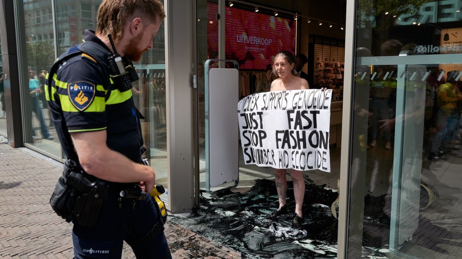 A naked Extinction Rebellion activist blocks the entrance of a major fashion retailer after pouring dark liquid on the floor, protesting the environmental impact of fast fashion on June 22, 2025 in The Hague, Netherlands. The campaigners are demonstrating against 'fast-fashion,' or the production of cheap, trendy clothing, which critics say is at the expense of social and environmental sustainability.