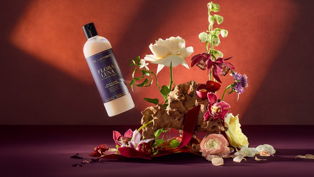the laundress laundry detergent bottle floating in the air next to a sculptural floral arrangement