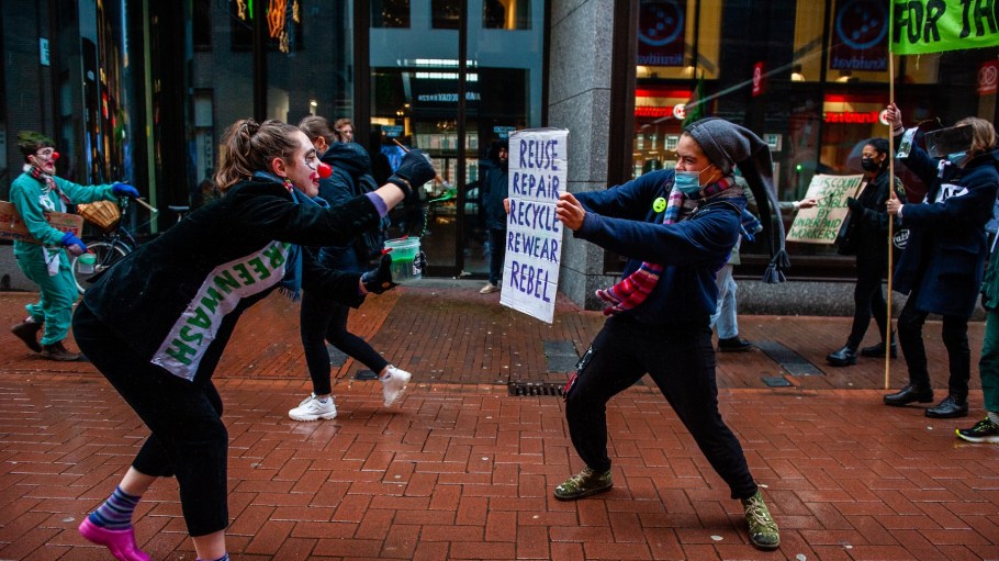 Two clowns representing the greenwashing practices carried out by fashion brands, are pretending painting with green paint, during a mocking Fast fashion parade organized by XR, against Black Friday in Amsterdam, on November 27th, 2021.