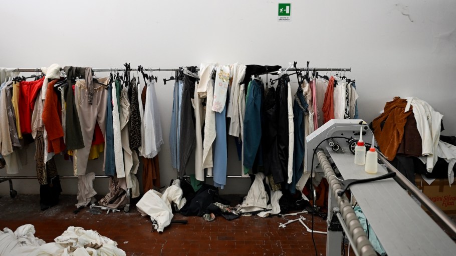 This photograph shows abandoned clothes in a fast-fashion outlet factory owned by a Chinese company in Prato, central Italy, on August 1, 2025. Chinese groups in the district thrive on the so-called "Prato system", long rife with corruption and widely documented irregularities, particularly in the fast-fashion sector, such as labour and safety violations plus tax and customs fraud. They pop up quickly and shut down just as fast, playing a cat-and-mouse game with authorities to avoid taxes or fines. Fabric is smuggled from China, evading customs duties and taxes, while profits are returned to China via illegal money transfers.