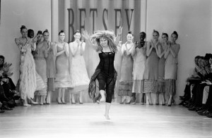 Designer Betsey Johnson cartwheels as she takes a bow during the finale with models Alek Wek, Irina Pantaeva, Gisele Bundchen, Jaime King and Jodie Kidd (Photo by David Turner/WWD/Penske Media via Getty Images)