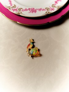 Tiffany & Co. brooch from the 2026 Blue Book collection in platinum, 18-karat yellow gold, fire opal, emerald, turquoise, light tsavorite and diamonds; Bernardaud Louis XV service plate and dinner plate.