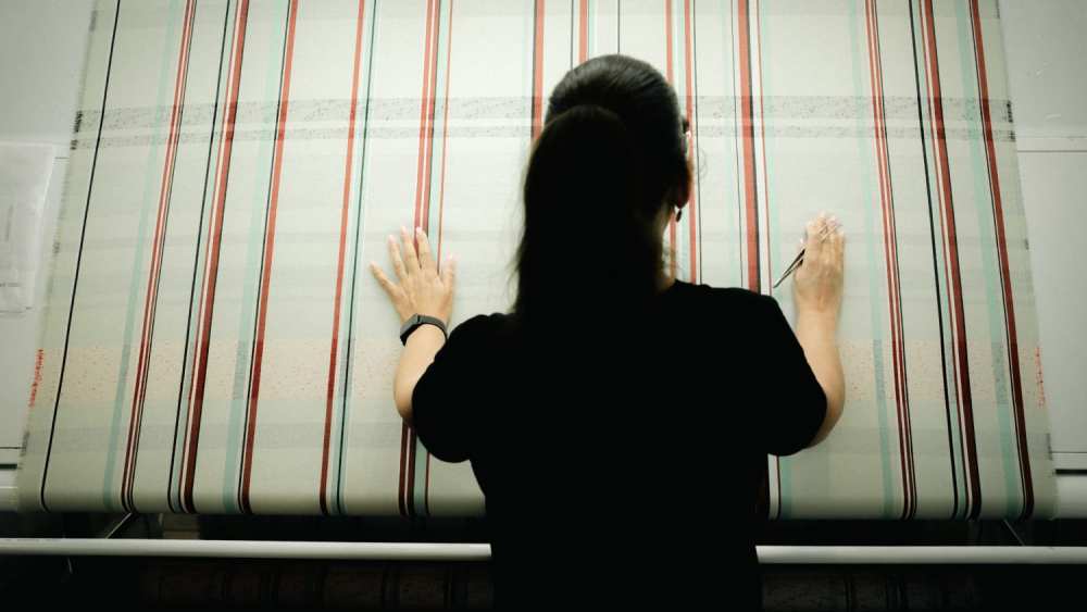 A worker oversees the weaving of a striped fabric from Chanel's cruise 2027 collection at the ACT3 atelier in Pau, southwest France