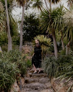 Chloé recycled technical sateen coat and organic silk mousseline dress; Khaite leather pumps; Chopard 18-karat white gold earrings with sapphires and diamonds from the high jewelry collection.