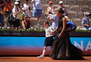 Japan's Naomi Osaka holds a mascots hand as she walks on Court Suzanne-Lenglen to player her women's singles match against Germany's Laura Siegemund on day 3 of the French Open tennis tournament at the Roland-Garros Complex in Paris on May 26, 2026. (Photo by Thomas SAMSON / AFP via Getty Images)